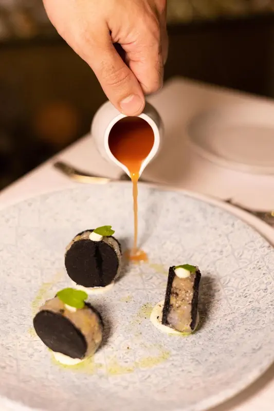 Présentation soignée d'un plat gastronomique avec une sauce versée sur des bouchées.