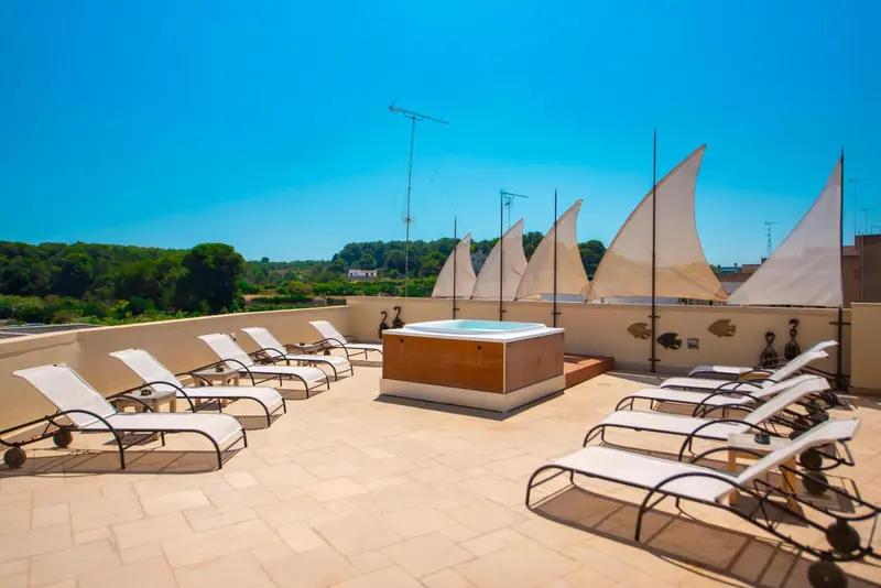 Terrasse avec jacuzzi et chaises longues ensoleillées.