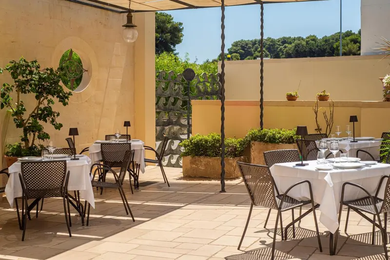 Tables dressées sur une terrasse ombragée avec vue sur un jardin.