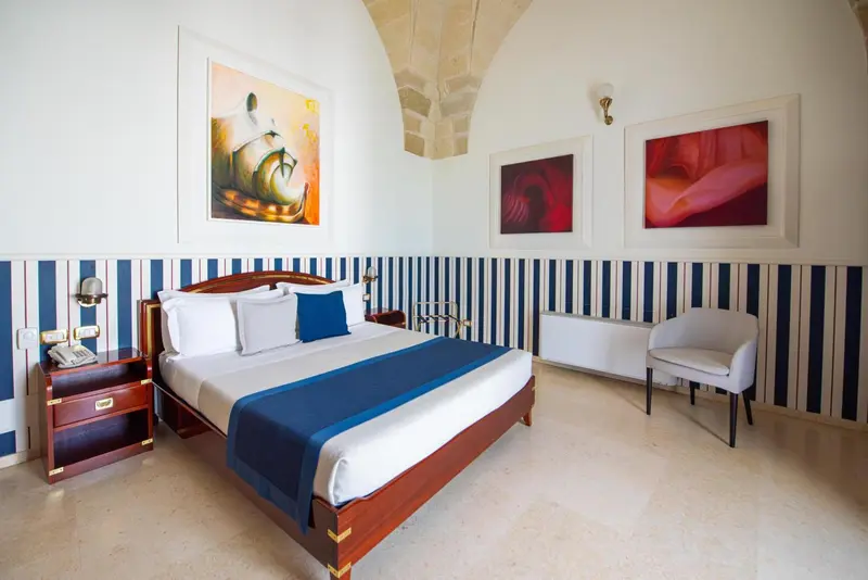 Une chambre lumineuse avec un lit double et des tableaux décoratifs.