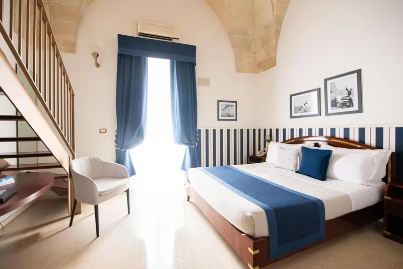 Une chambre lumineuse avec un lit double et un fauteuil.