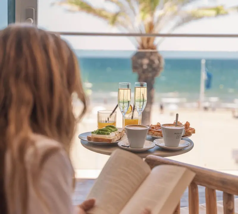 Une personne déguste un petit-déjeuner face à la mer.