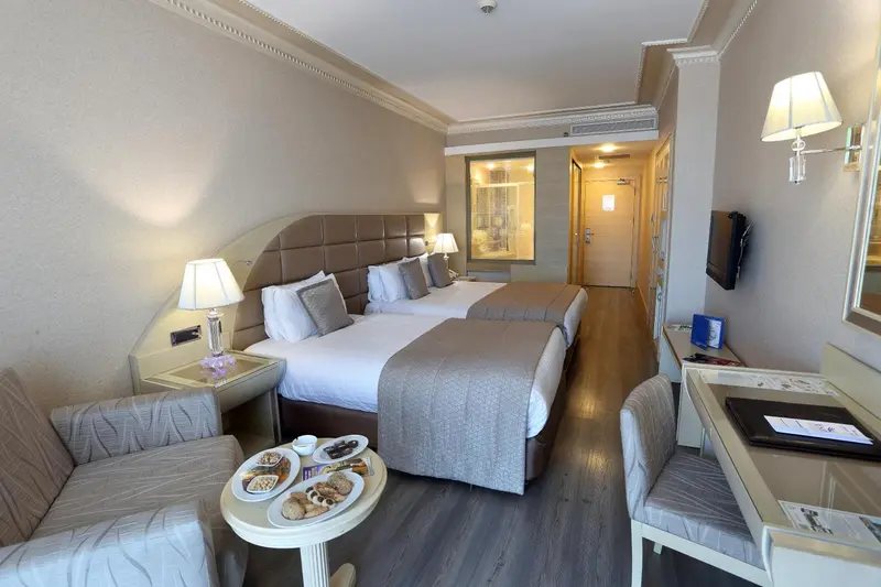 Chambre lumineuse avec un grand lit et un coin salon.