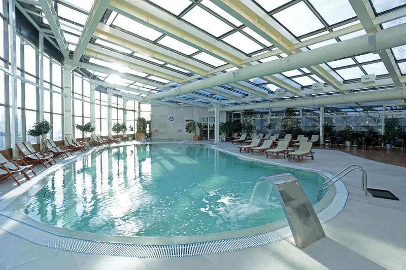 Une piscine intérieure lumineuse avec des transats alignés sur le bord.