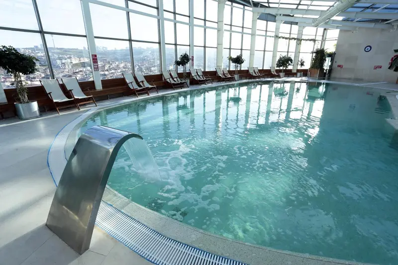 Une piscine intérieure avec une vue panoramique sur la ville.