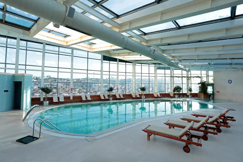 Une piscine intérieure lumineuse offre une vue panoramique sur la ville.