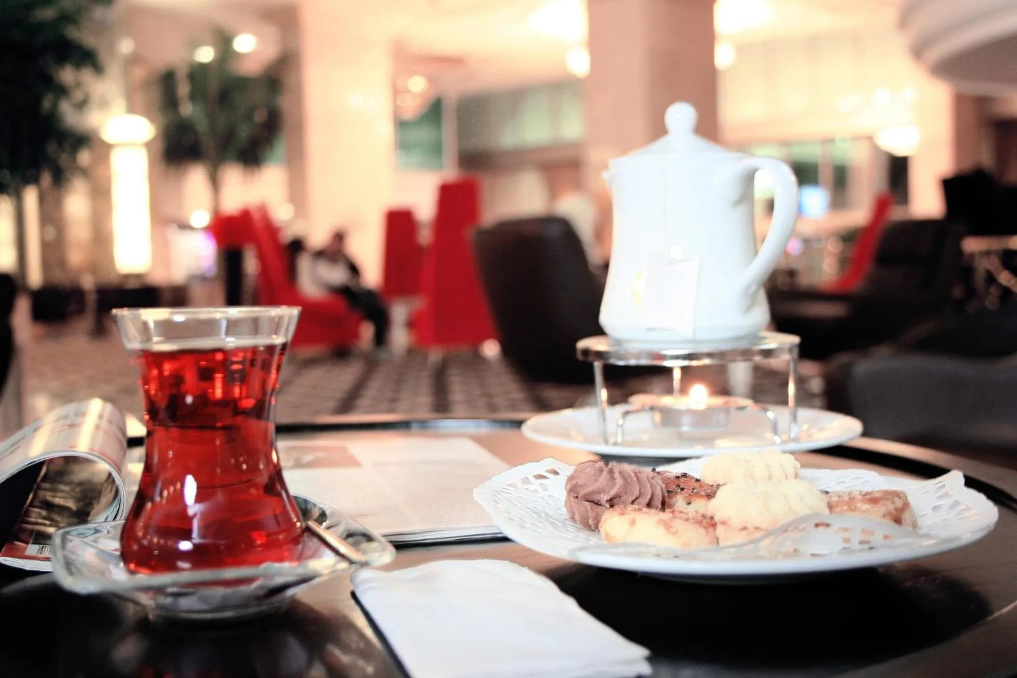 Une table basse présente une théière, un verre de thé et une assiette de pâtisseries.