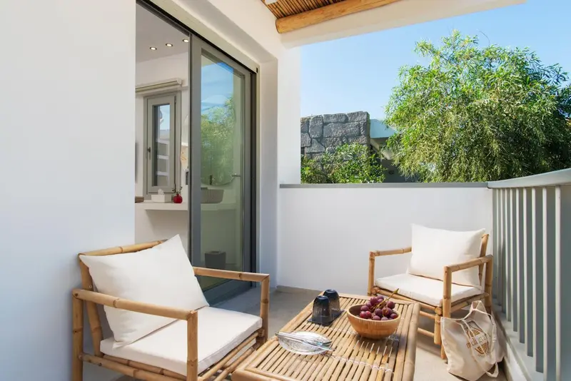 Terrasse aménagée avec mobilier en rotin et vue sur la végétation.