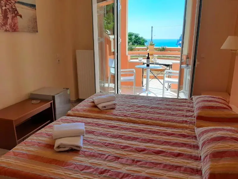 Une chambre lumineuse s'ouvre sur une terrasse avec vue sur la mer.
