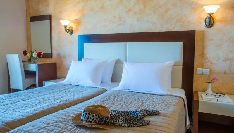 Une chambre d'hôtel avec un grand lit recouvert d'une courtepointe et un miroir au mur.