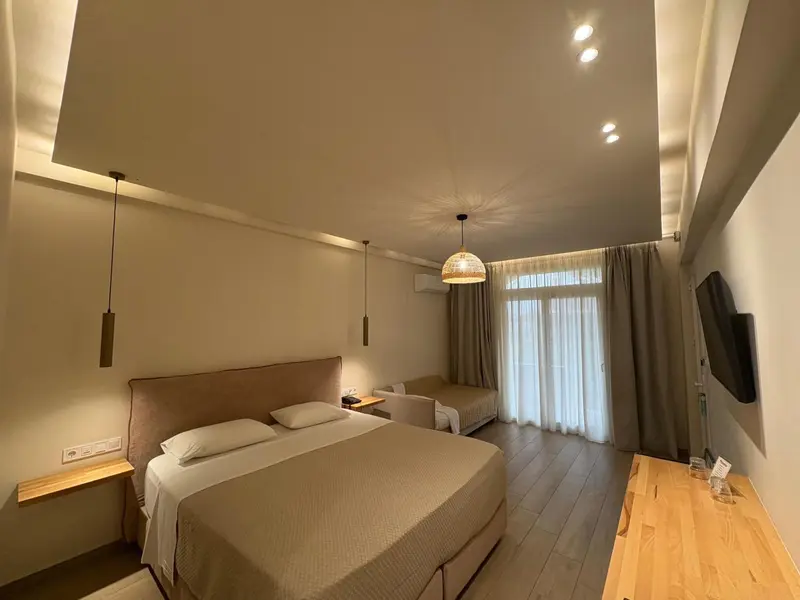 Chambre lumineuse avec un grand lit et un accès à une terrasse.