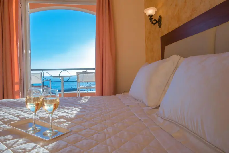 Une chambre avec un lit et une vue sur la mer depuis un balcon.