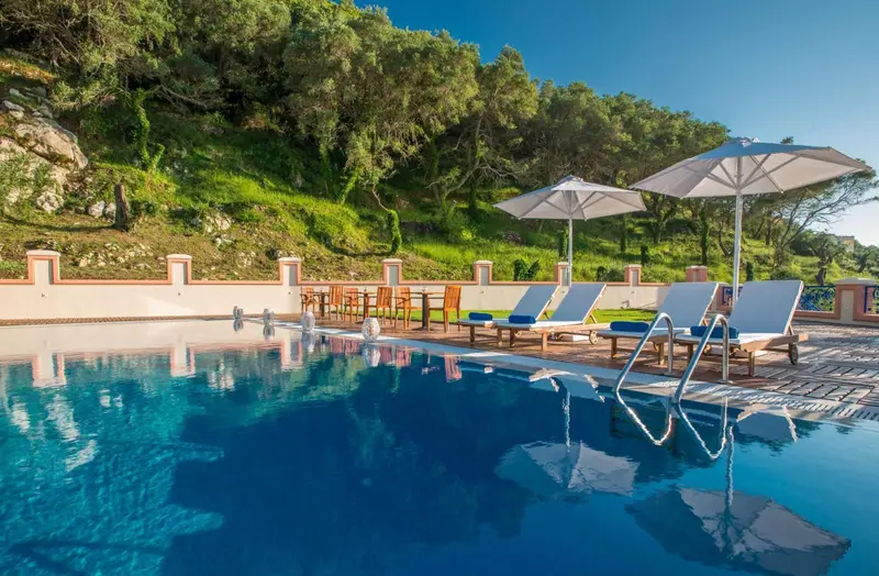 Transats et parasols bordent une piscine bleu clair.