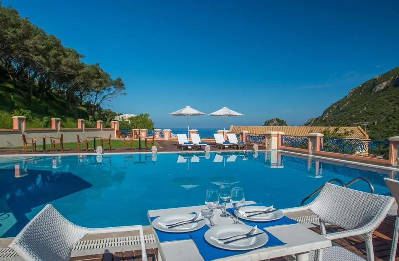 Terrasse avec piscine et table préparée pour un repas.