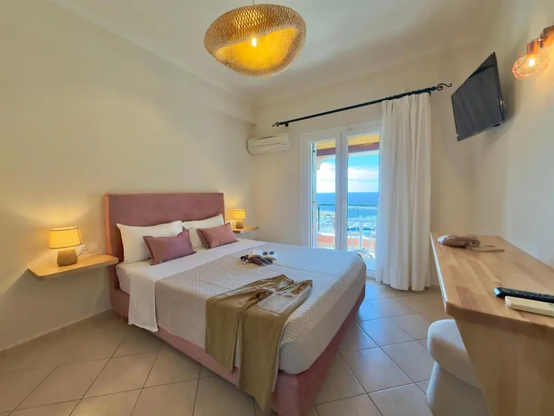 Une chambre lumineuse avec un lit double et un accès à un balcon.