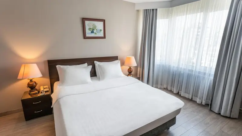 Une chambre lumineuse avec un grand lit et des rideaux clairs.