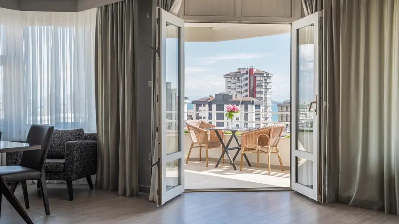 Une terrasse ensoleillée offre une vue sur des bâtiments et la mer.