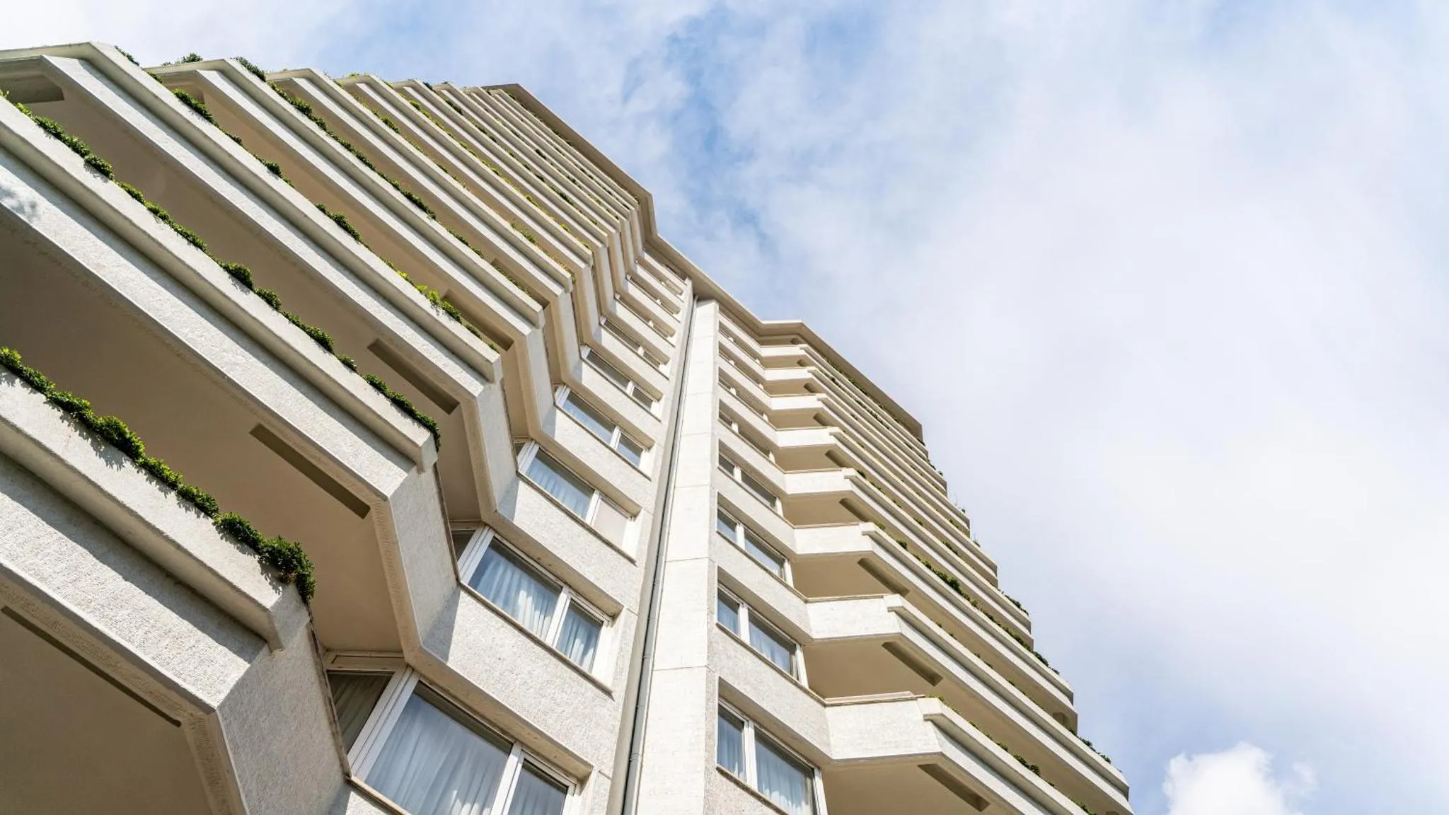 Vue en contre-plongée d'un immeuble blanc aux nombreux balcons.