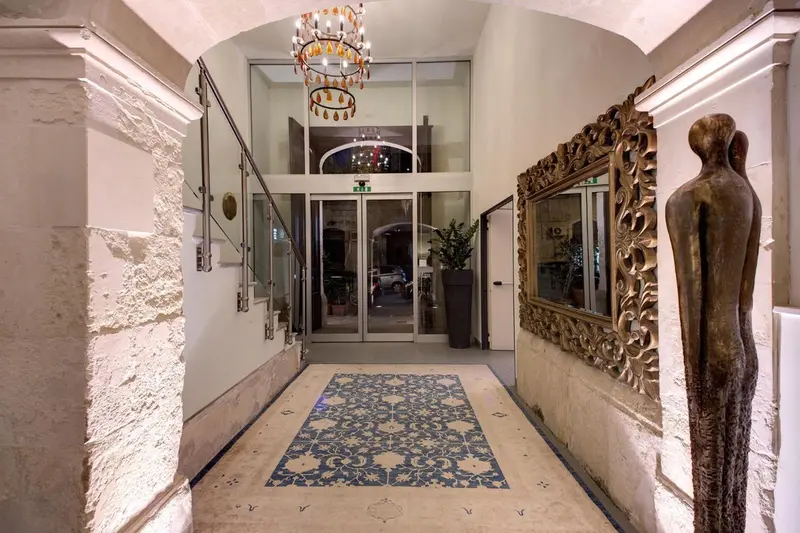 Hall d'entrée lumineux avec un grand miroir et un lustre décoratif.