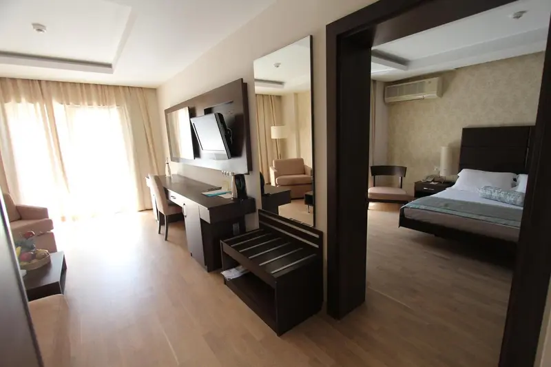 Une chambre lumineuse avec un espace salon et un lit fait.