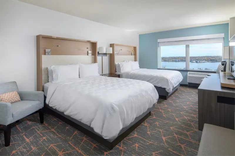 Chambre d'hôtel lumineuse avec deux lits et vue sur l'océan.