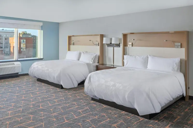 Deux lits jumeaux avec des couvertures blanches dans une chambre d'hôtel.