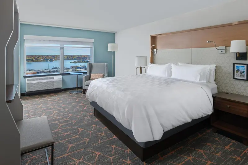 Chambre lumineuse avec un grand lit et une vue sur la mer.