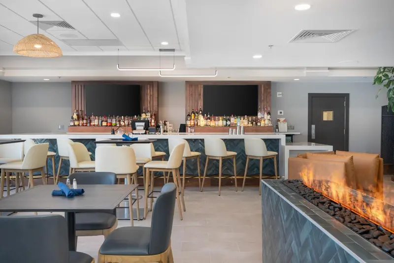 Un bar moderne avec des tabourets et des tables, et une cheminée décorative.