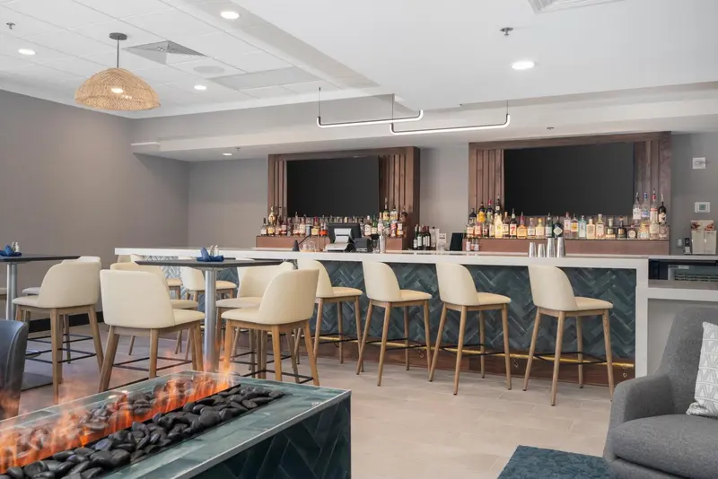 Un bar moderne avec des tabourets et un comptoir bien garni de bouteilles.