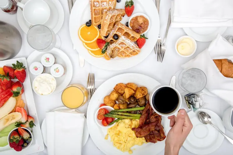Table dressée avec un copieux petit-déjeuner composé de gaufres, de fruits et d'oeufs.