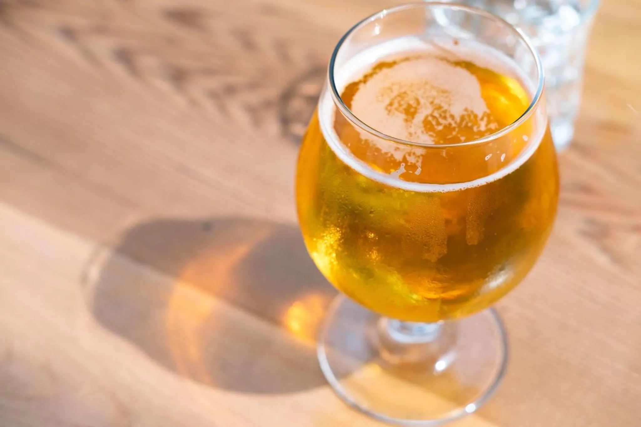 Un verre de bière blonde mousseuse sur une table en bois.