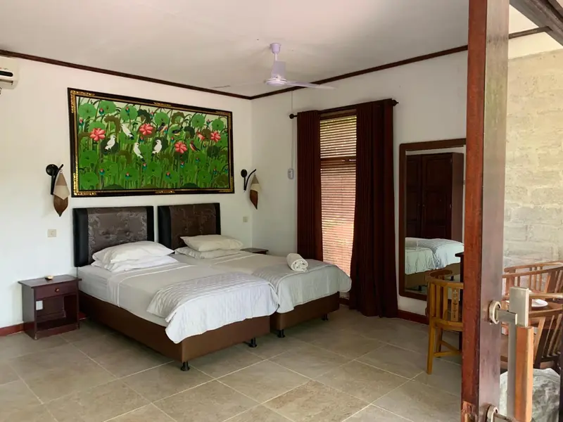 Une chambre lumineuse avec un grand lit et un tableau floral.