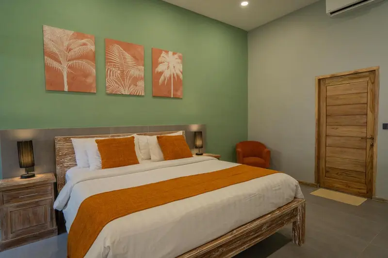 Une chambre lumineuse avec un grand lit et des œuvres d'art murales.