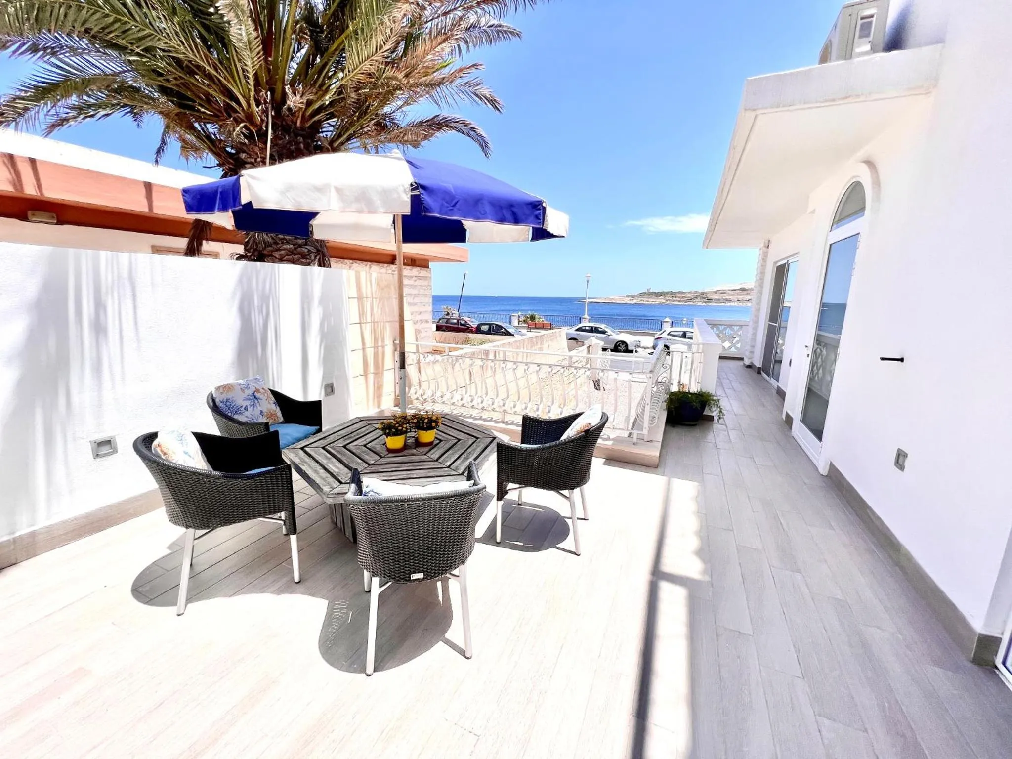 Terrasse aménagée avec table et chaises, vue sur la mer.