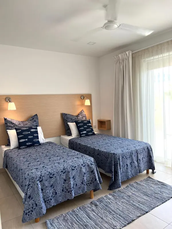 Chambre lumineuse avec deux lits simples et une décoration marine.
