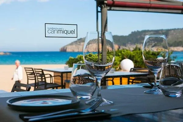 Une table est dressée avec des verres et une assiette sur une terrasse en bord de mer.