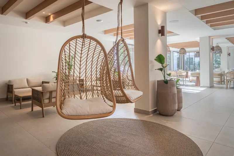 Espace de détente intérieur avec fauteuils suspendus en rotin.