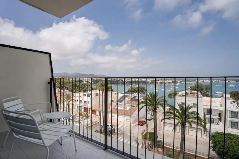Vue d'une terrasse avec des fauteuils et une vue sur la mer et la ville.