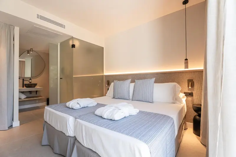 Une chambre lumineuse avec un grand lit et un espace salle de bain ouvert.