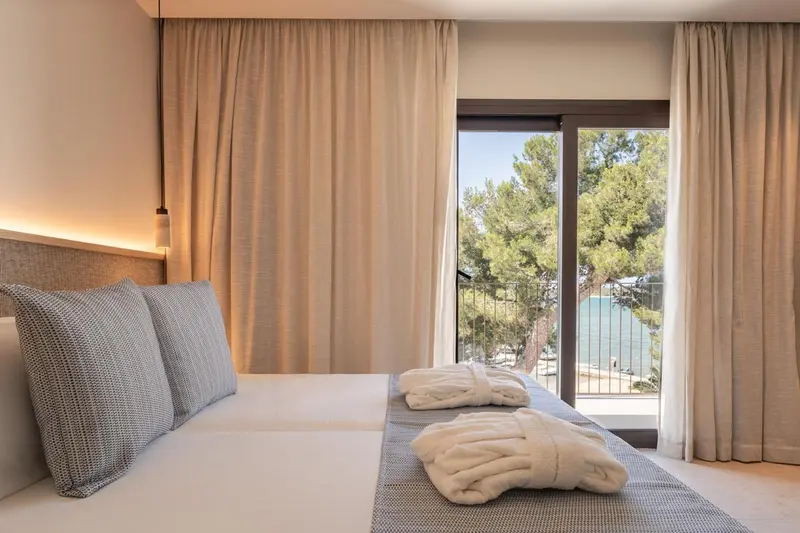 Une chambre lumineuse avec un lit fait et une vue sur la mer.