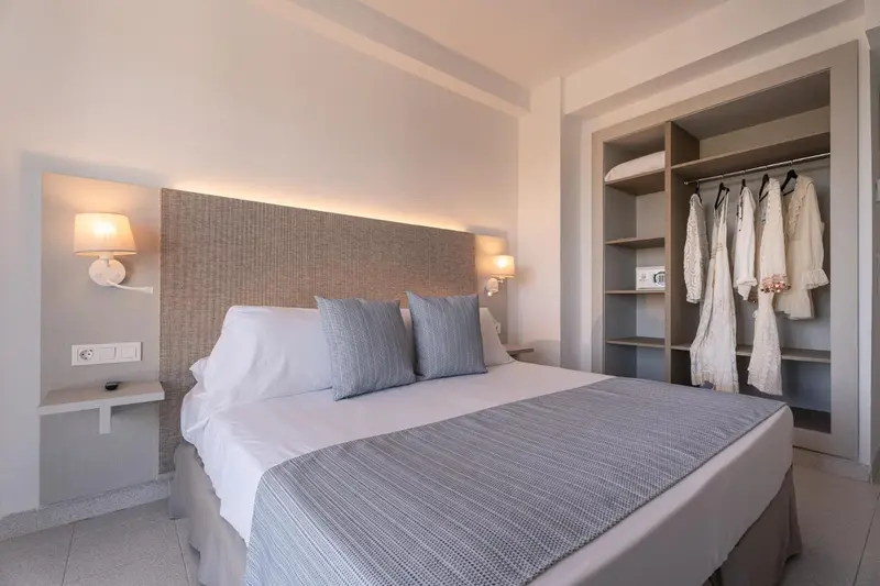 Une chambre lumineuse avec un grand lit et un espace de rangement ouvert.