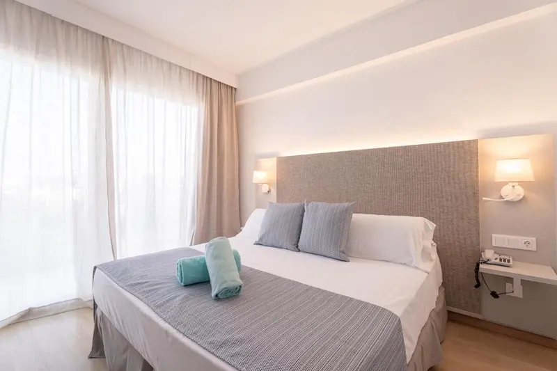 Une chambre lumineuse avec un grand lit et des rideaux clairs.