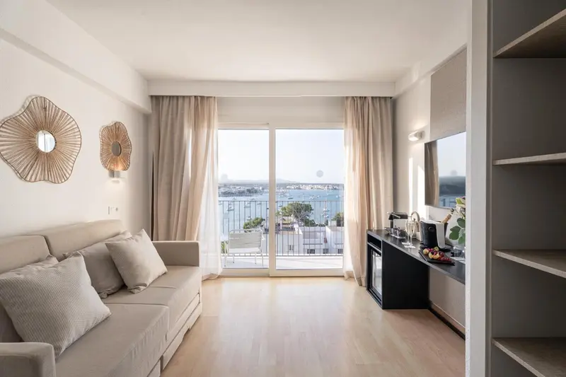 Espace de détente lumineux avec canapé et vue sur la mer.