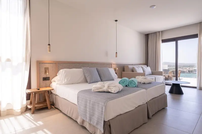 Chambre lumineuse avec un grand lit et un espace détente.