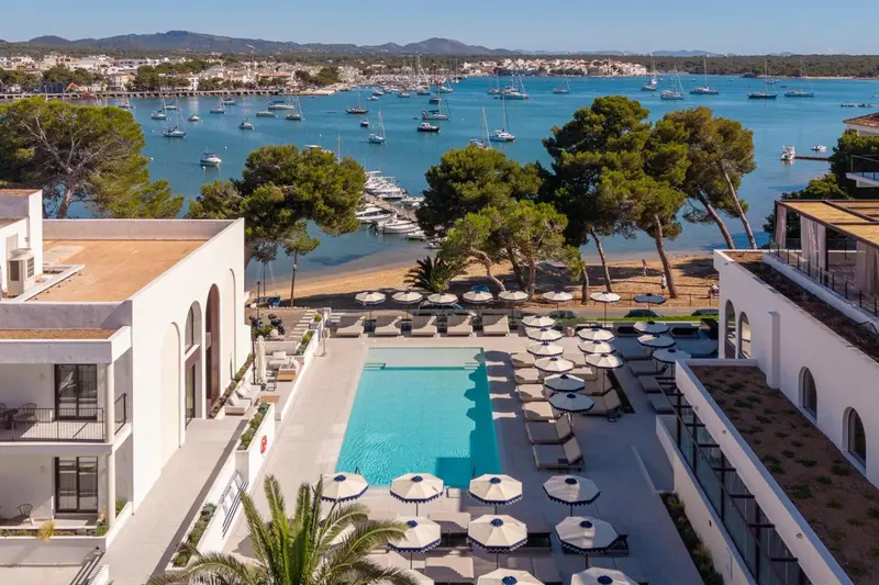 Vue aérienne d'une piscine d'hôtel avec des transats et une plage en contrebas.