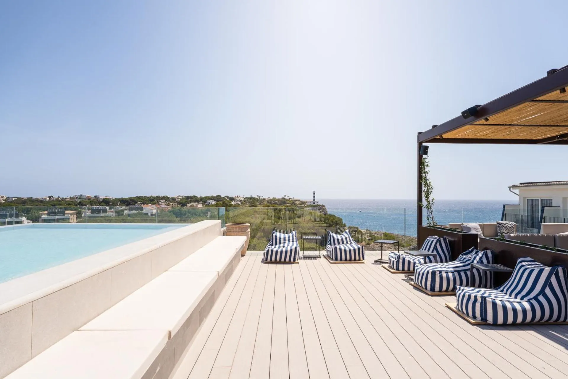 Terrasse avec transats et piscine à débordement donnant sur la mer.