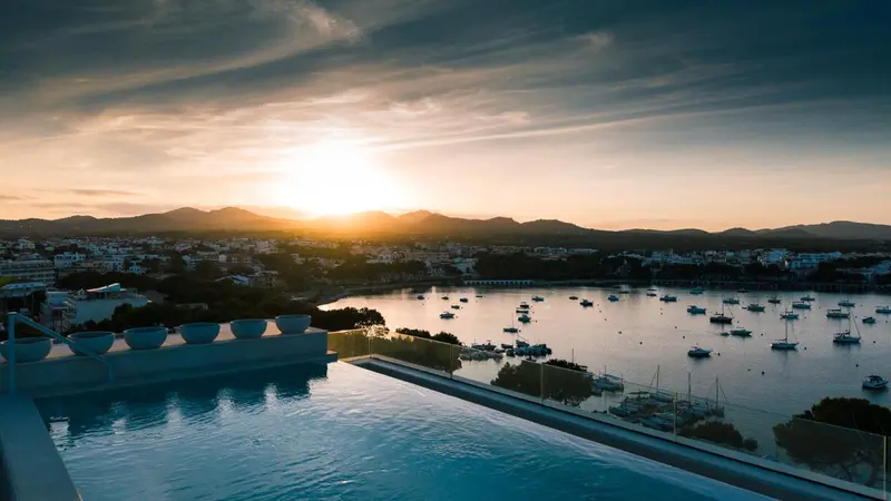Vue d'une piscine à débordement sur une baie au coucher du soleil.