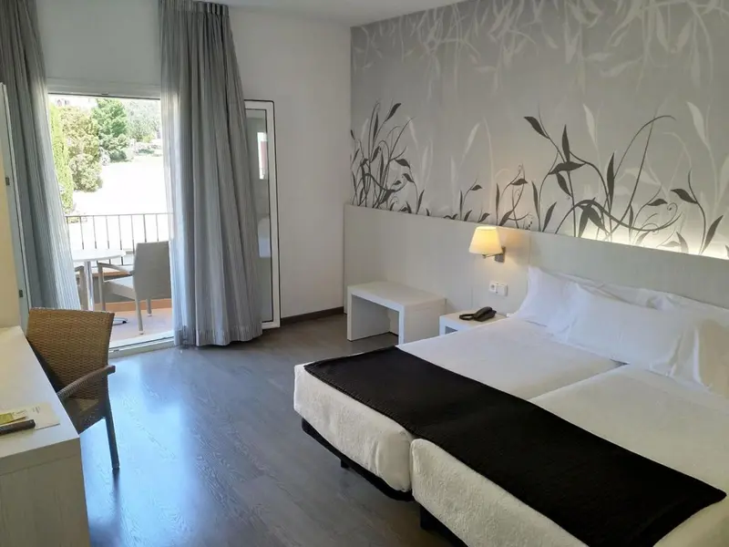 Une chambre lumineuse avec un lit double et un accès à un balcon.