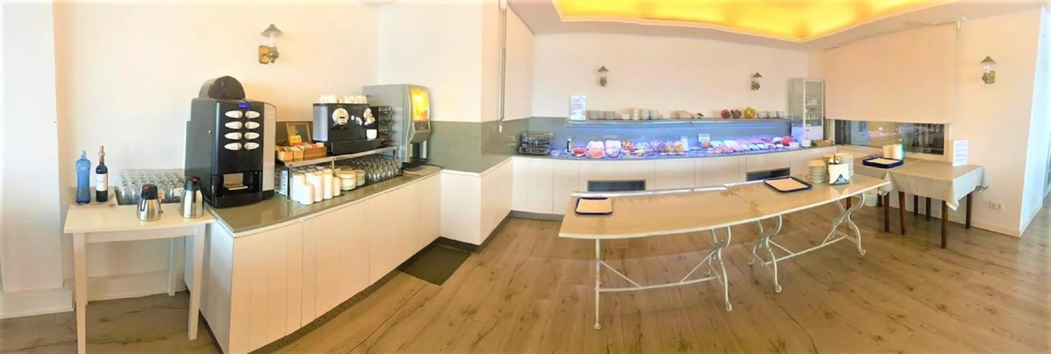 Un comptoir de buffet propose une variété de plats et de boissons dans une salle lumineuse.