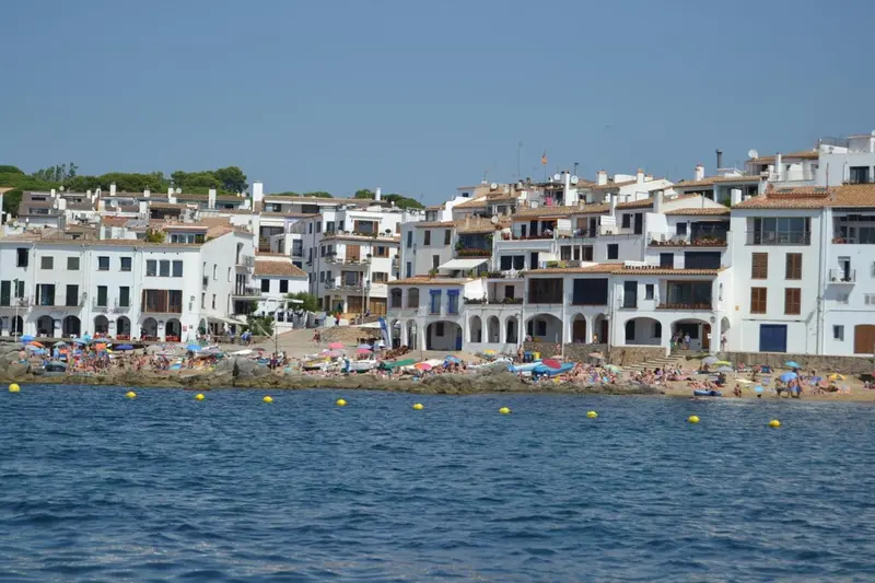 Vue d'une plage bordée de bâtiments blancs et de parasols colorés.